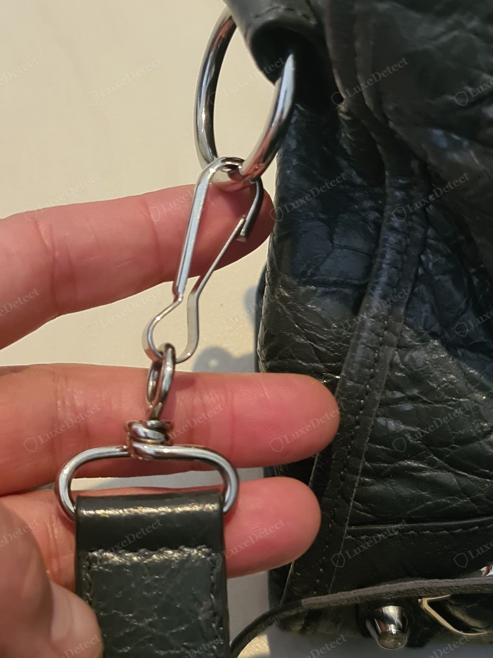 Genuine Balenciaga City handle attachment — silver-hardware version: an S-hook clasp, split ring and D-ring linking a knotted leather strap tab, on black distressed lambskin with deep natural crinkle