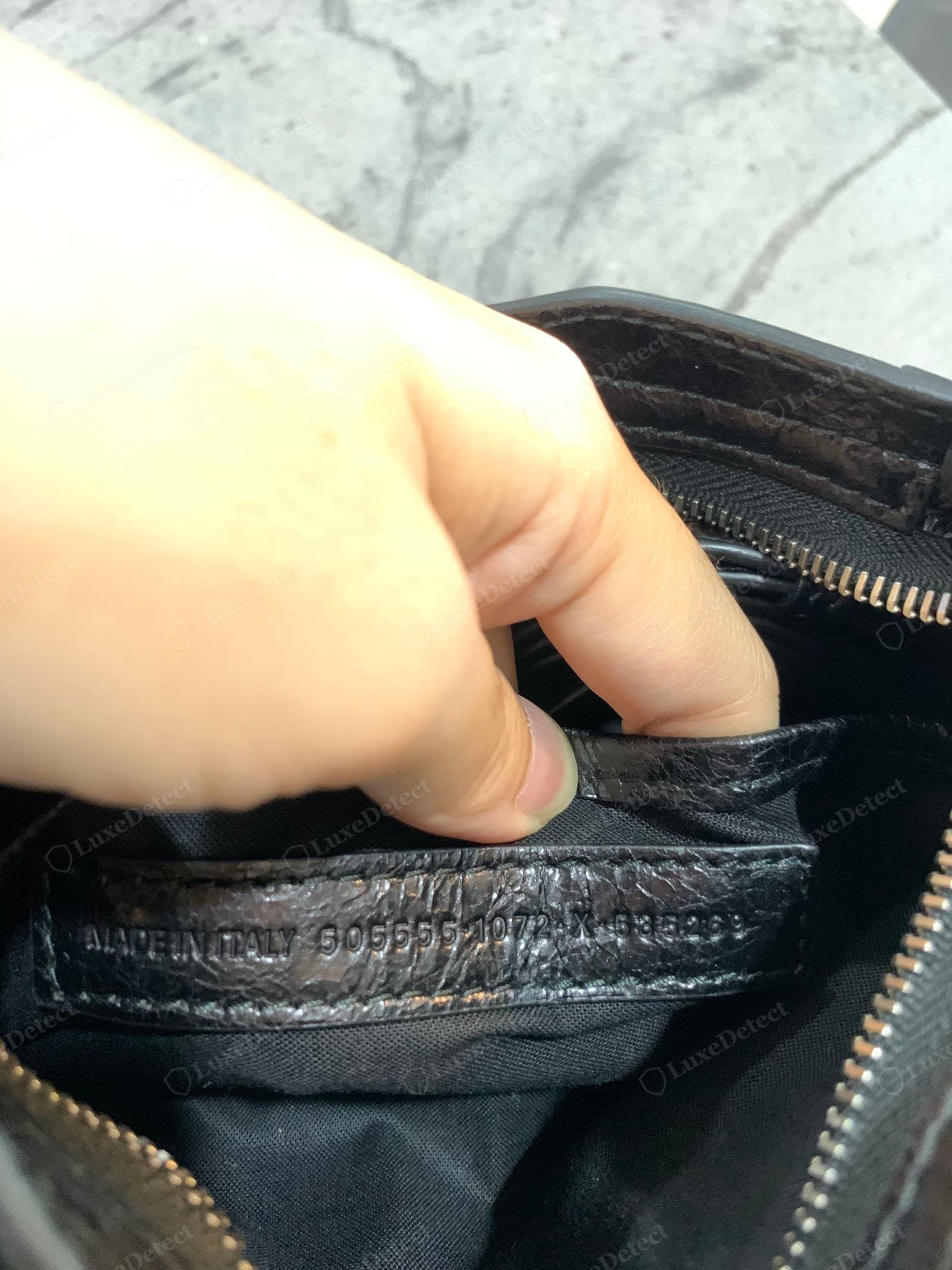 Genuine Balenciaga City interior tab — "MADE IN ITALY 505550 1072 X 535269" blind-embossed (no ink) into a small distressed-leather tab sewn into the black canvas lining seam