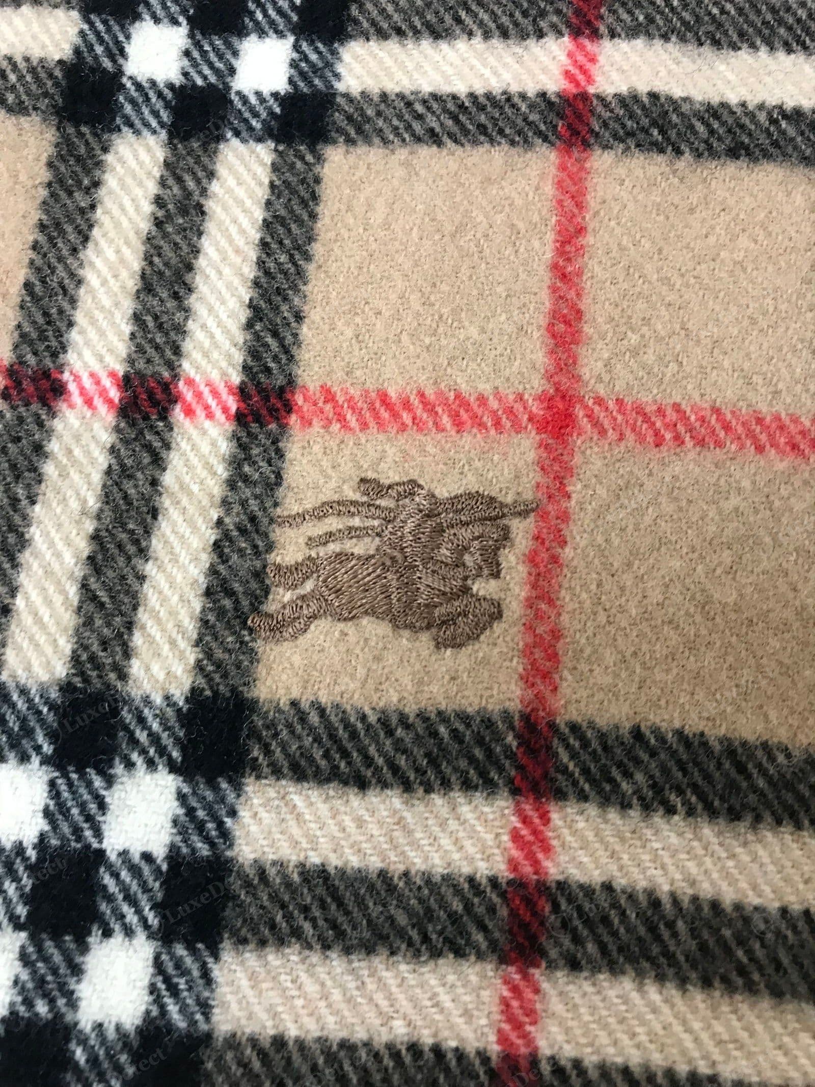 Counterfeit Burberry scarf logo — a fuzzy, mis-proportioned, or printed "BURBERRY", or the wrong typeface