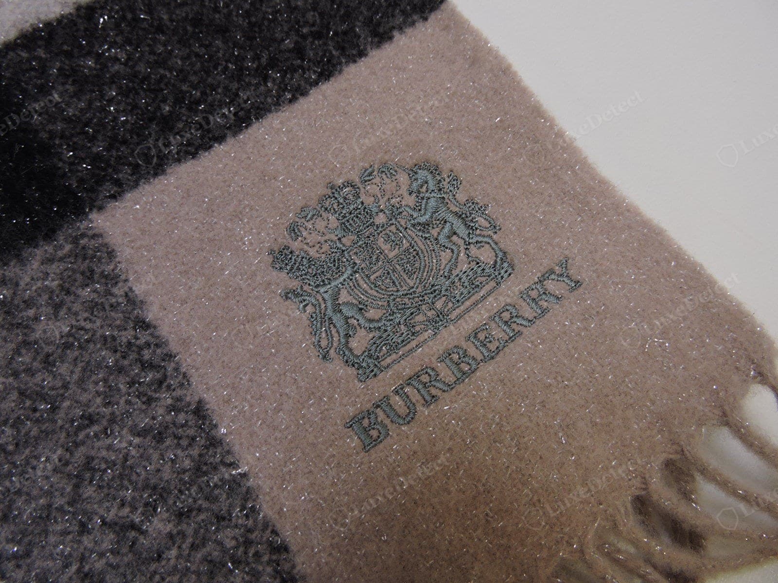 Genuine Burberry scarf woven logo — the "BURBERRY" wordmark woven into the scarf, sharp and correctly proportioned