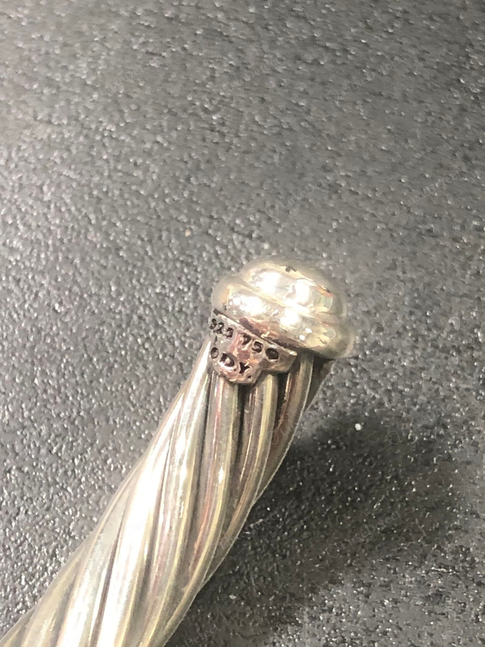 Counterfeit David Yurman cable — a soft shallow twist with the grooves nearly filled, mushy definition, a plain domed cap, and a crude "925 750 / D.Y." stamp on the collar