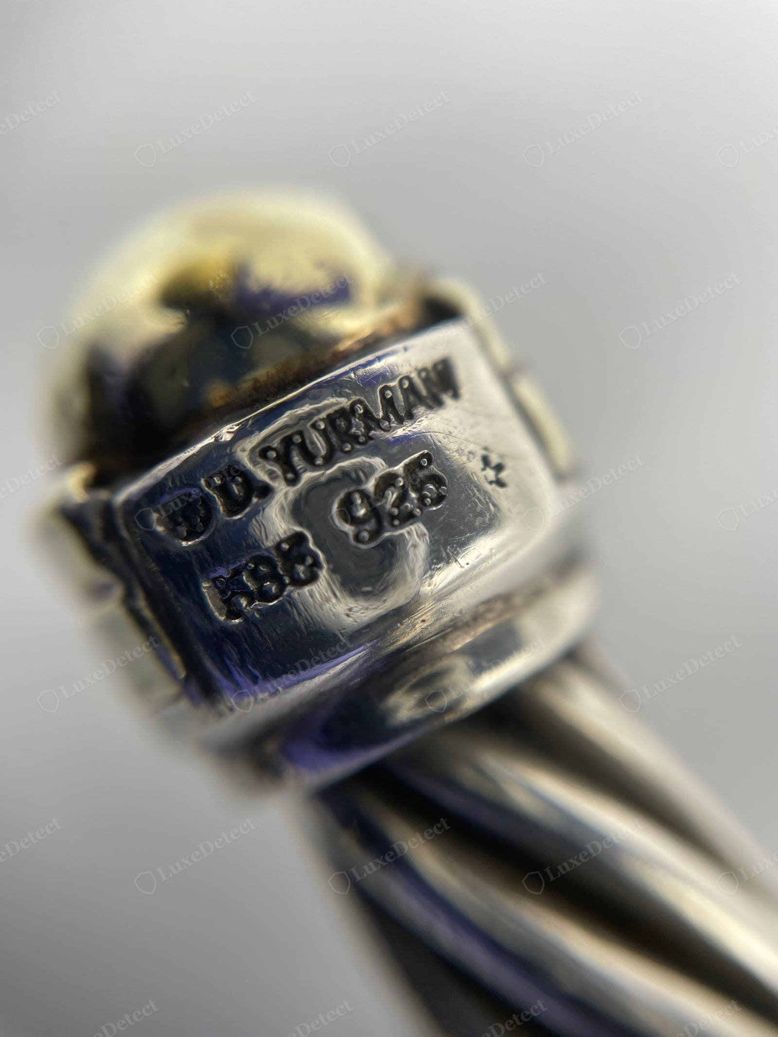 Counterfeit David Yurman hallmark — "D. YURMAN / ABS 925" struck crooked and shallow, letters of uneven depth with blobby edges, the metal pitted around the stamp