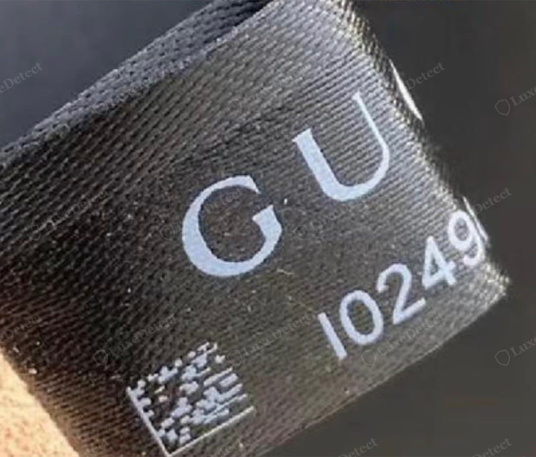Counterfeit Gucci black label showing blurry lighter-grey printing, rounded letterforms, and a coarser QR code — a different serial number beginning with a different digit block