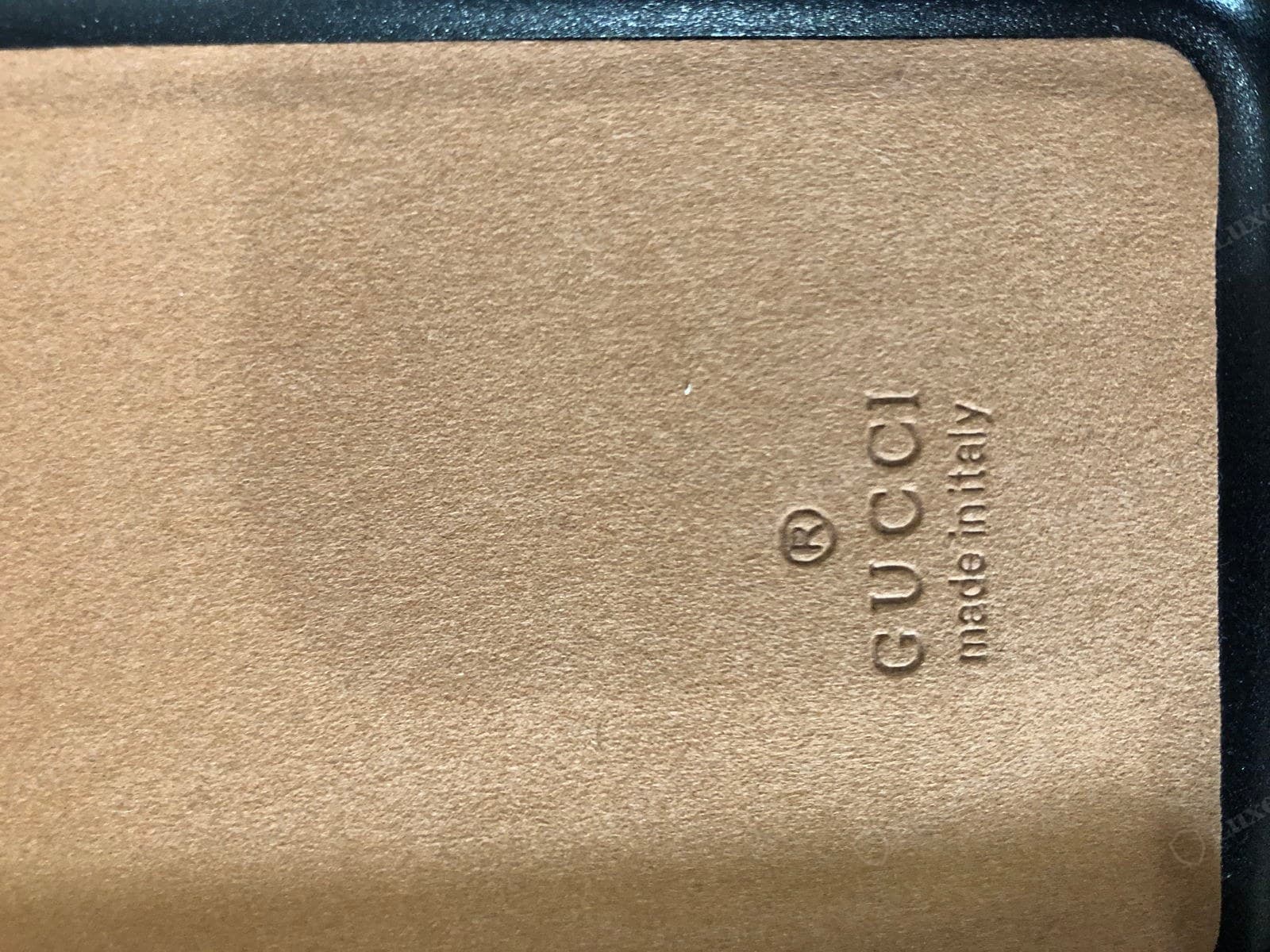 Counterfeit Dionysus interior stamp: "® GUCCI made in italy" embossed directly into thin tan microsuede rather than on a leather tab, the letters running vertically and the emboss shallow and uneven