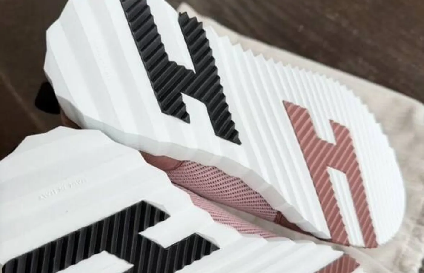 Both soles of a rose pair — the forefoot and heel H's are crisp and match left-to-right; the white midsole edge is a regular scalloped wave