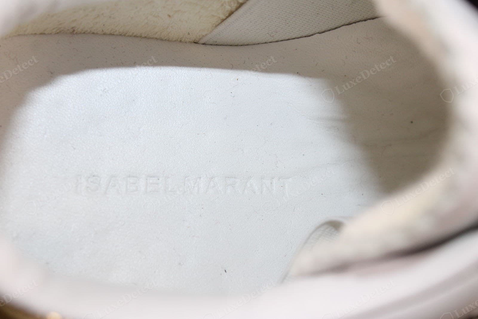Counterfeit Isabel Marant branding — a sneaker insole blind-embossed "ISABELMARANT" with the words nearly run together, the letter spacing cramped and the stamp shallow and uneven