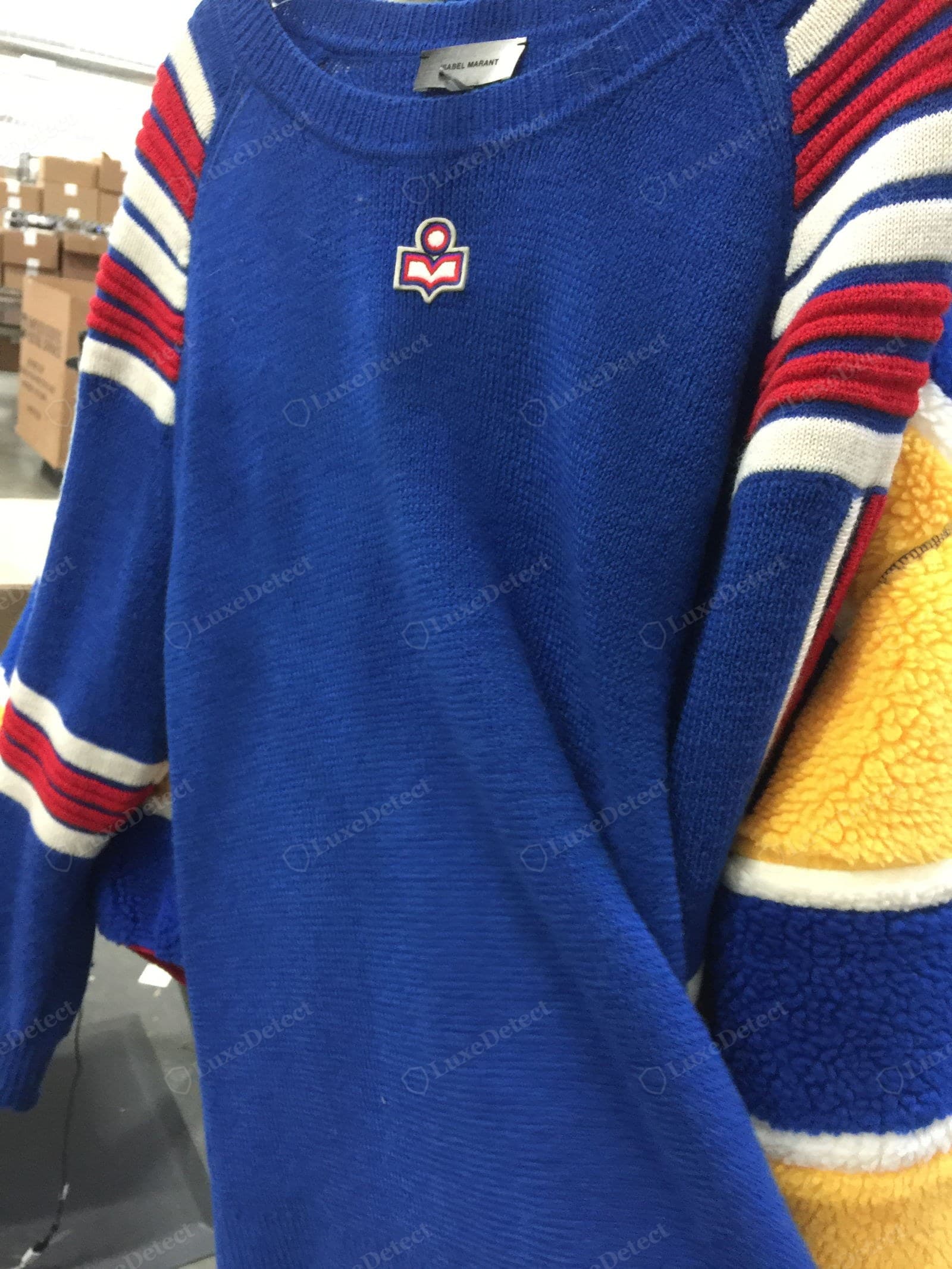 Genuine Isabel Marant branding — a cobalt sweater with "ISABEL MARANT" woven cleanly at the neck and the stylised woman-with-book "M" logo embroidered on the chest in red, white and blue, the outlines crisp and the motif flat