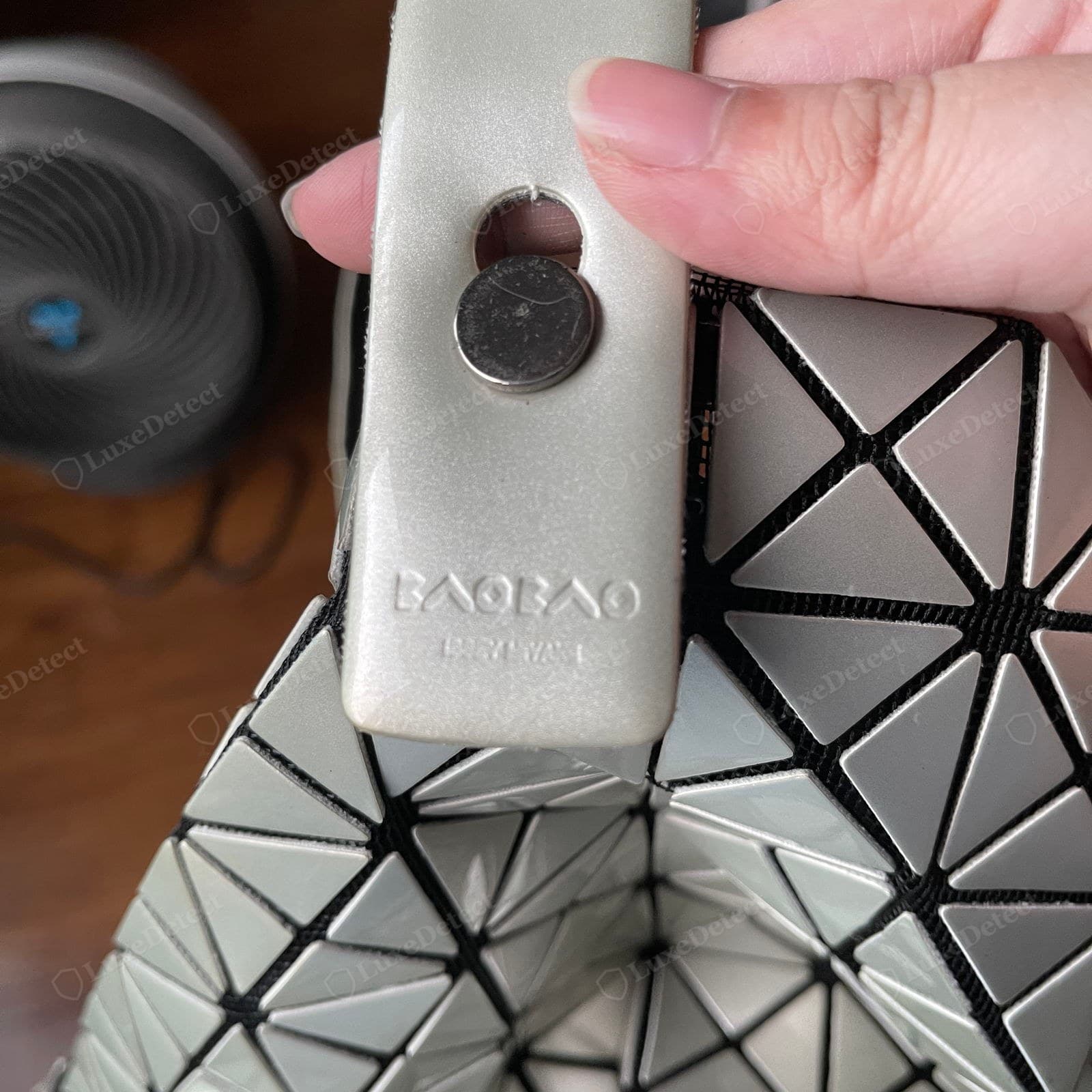Counterfeit BAOBAO — wavy unevenly bonded triangles with inconsistent gaps, glossy patches on the PVC, and loose black edge webbing pulling away from the tiles