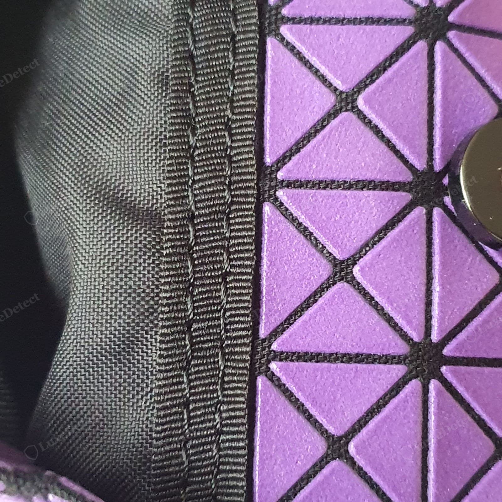 Genuine BAOBAO ISSEY MIYAKE — evenly sized matte PVC triangles bonded flat and square to a fine flexible mesh backing, consistent gaps, a regular grid, cleanly bound edges