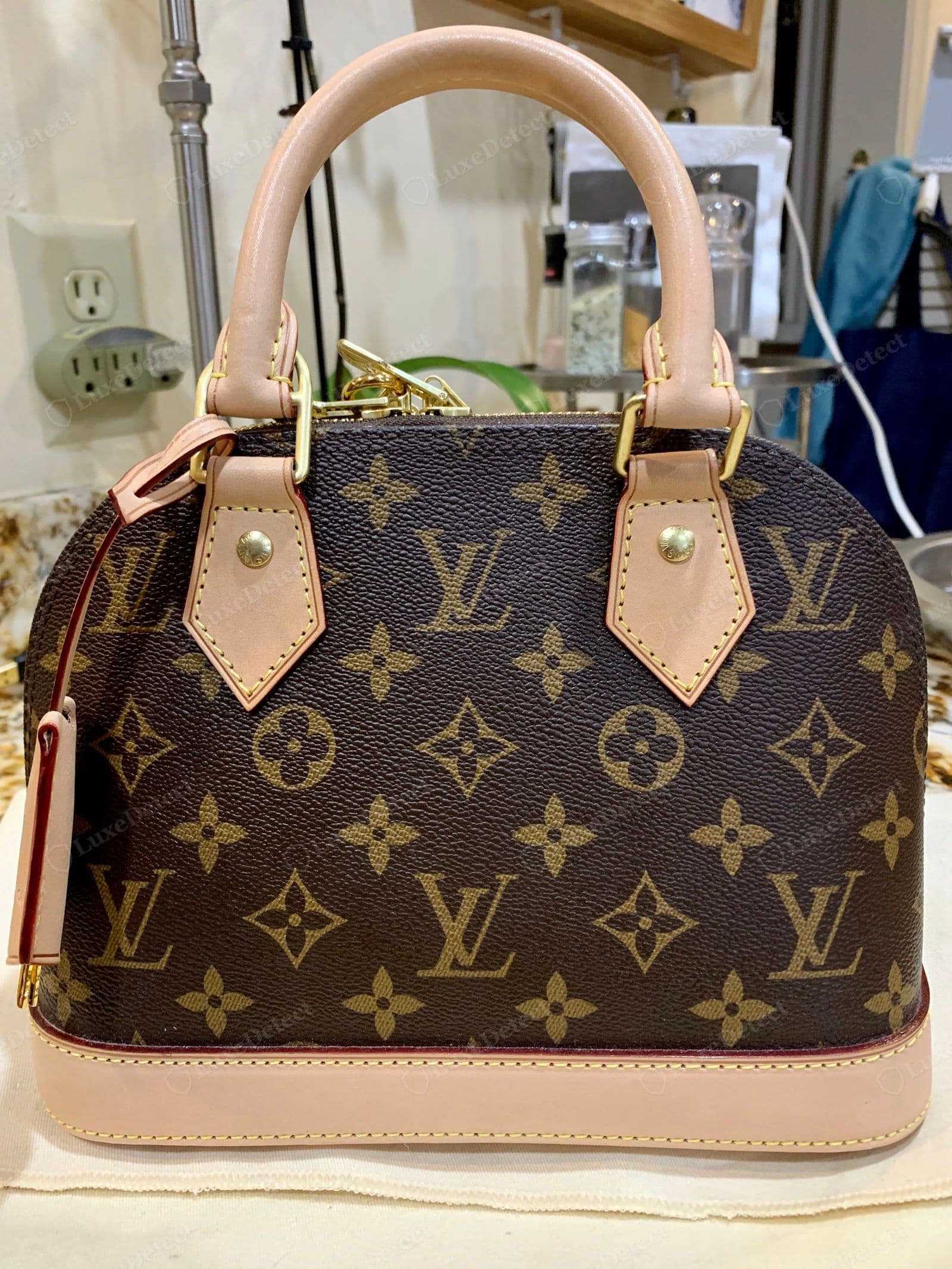 Counterfeit LV Alma — the Monogram sits slightly large and reads too bold and dark with a faint plastic sheen, and the vachetta is a flat uniform pinkish-tan with none of the natural tonal variation of genuine raw leather