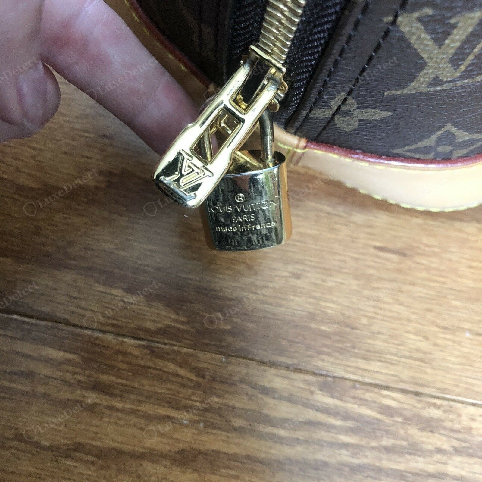 Counterfeit LV Alma zipper — a soft or mis-stamped pull, a catching slider, tape in a mismatched colour