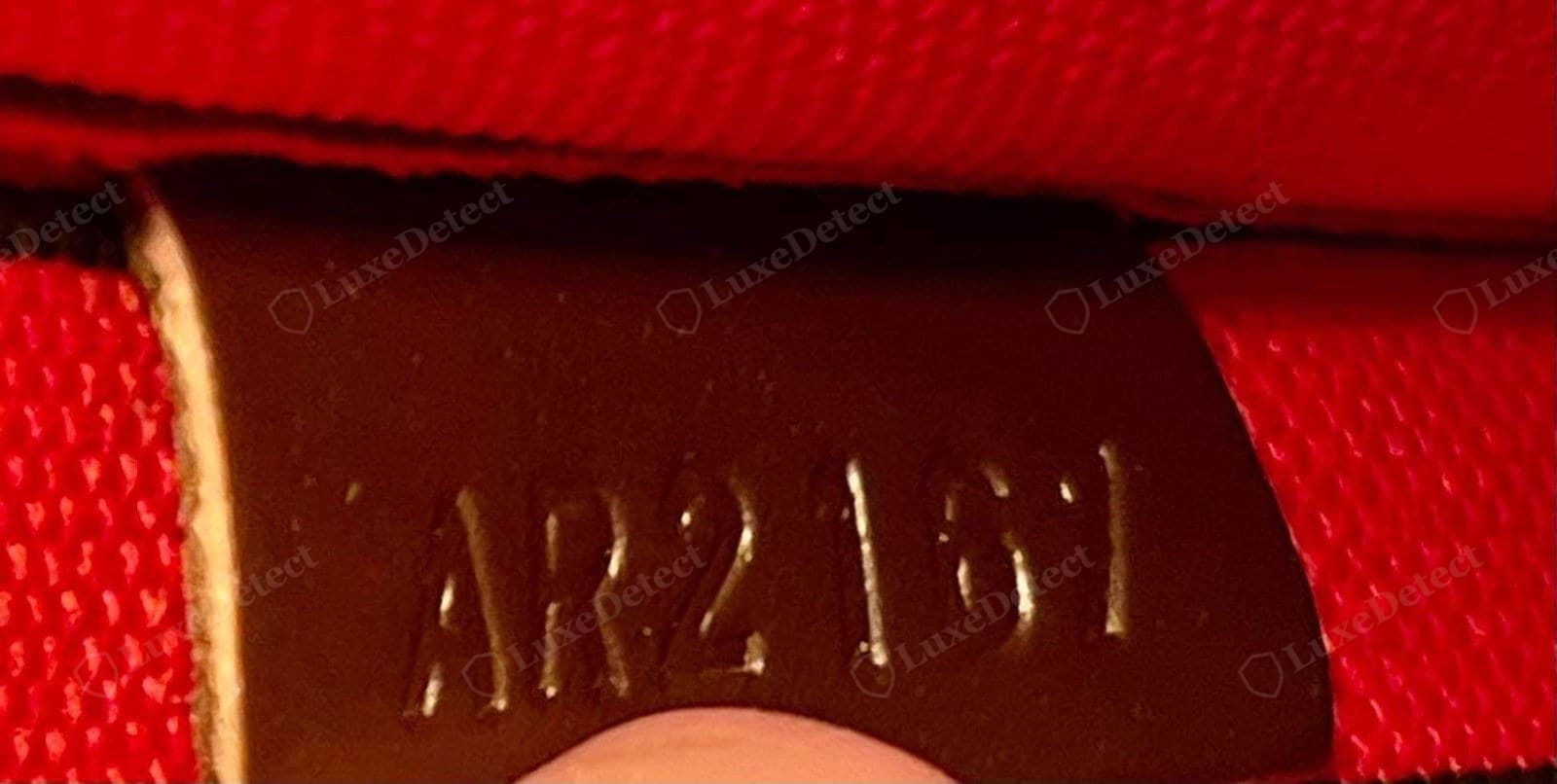Genuine LV date code — two letters and four digits ("AR2161" = week 21 of 2016) heat-embossed into a leather tab against a red microfibre lining, in the same font and depth as the main stamp