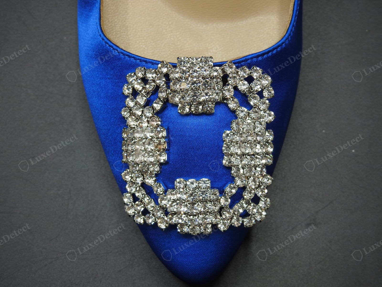 Genuine Manolo Blahnik Hangisi buckle — the rectangular crystal-cluster buckle on cobalt satin, bright clear cut crystals prong-set in the dense floral arrangement, clean silver settings, sitting flat and centred on the vamp