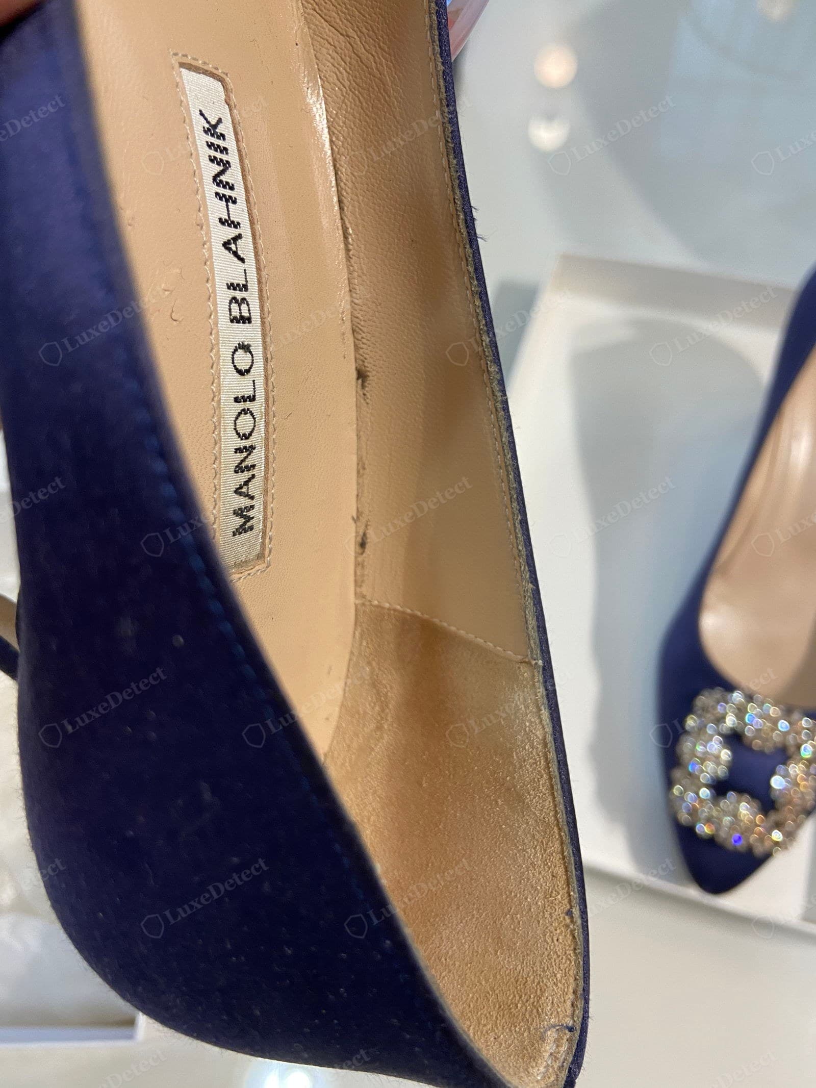 Genuine Manolo Blahnik insole — "MANOLO BLAHNIK" woven cleanly with even letter spacing and the correct typeface, neatly stitched into the leather footbed, the bright genuine crystal buckle catching light behind it