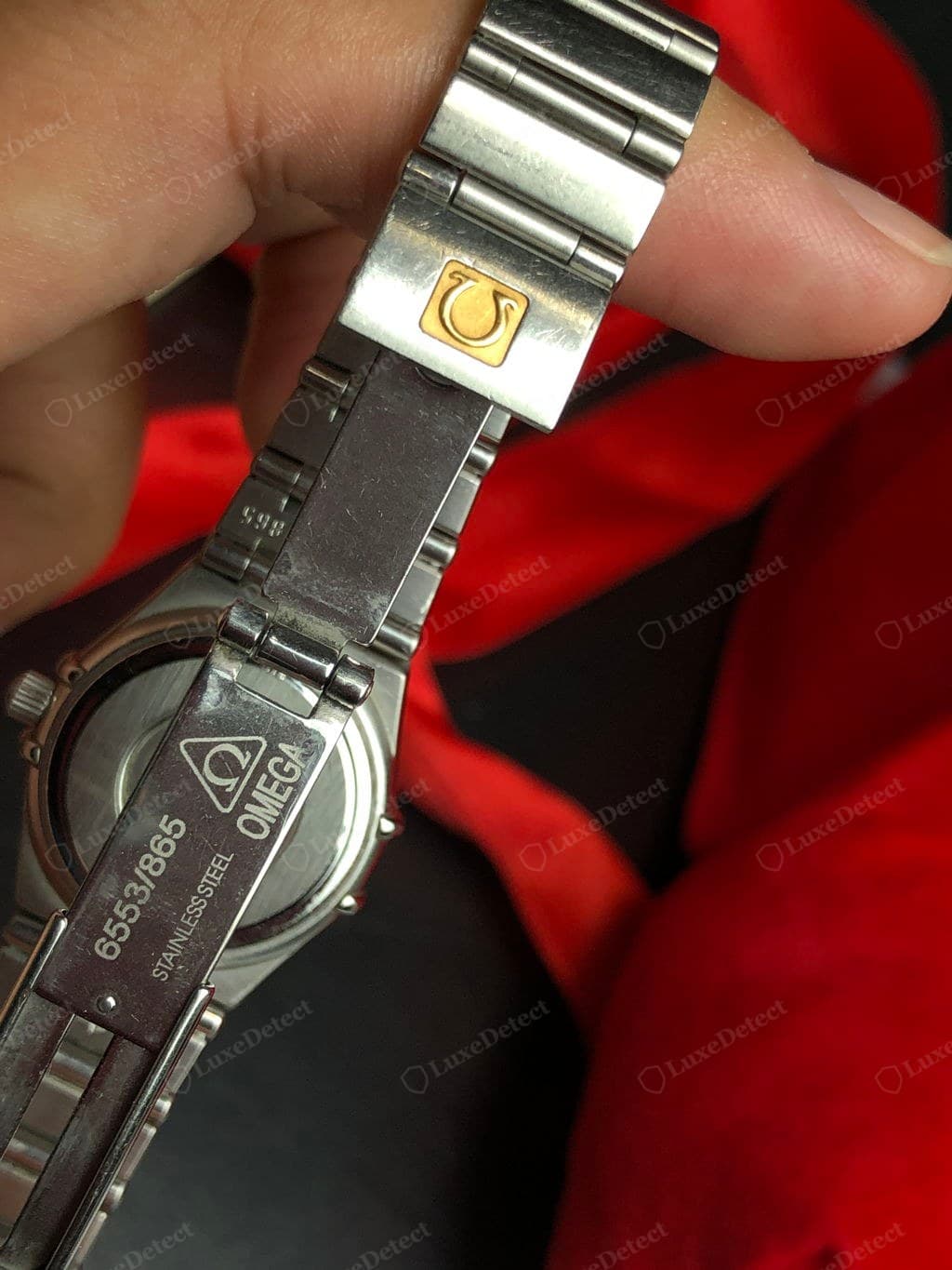 Counterfeit Omega bracelet and clasp — uneven finishing, a shallow or misshapen clasp logo, gaps or rattle at the end links