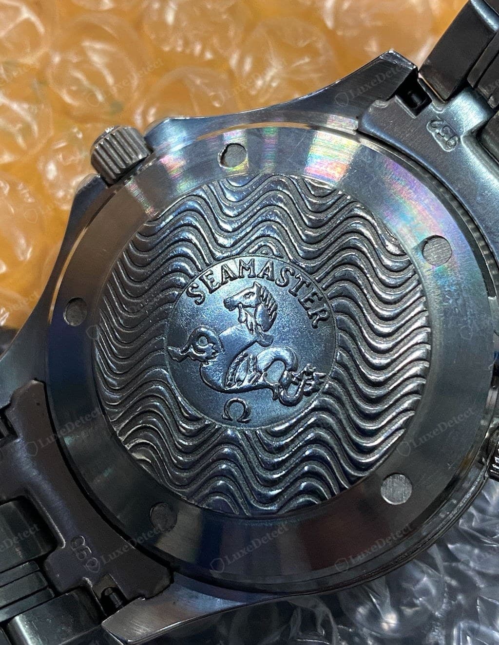 Counterfeit Omega caseback — flat, soft, or shallow relief; wording, font, or spacing wrong for the reference