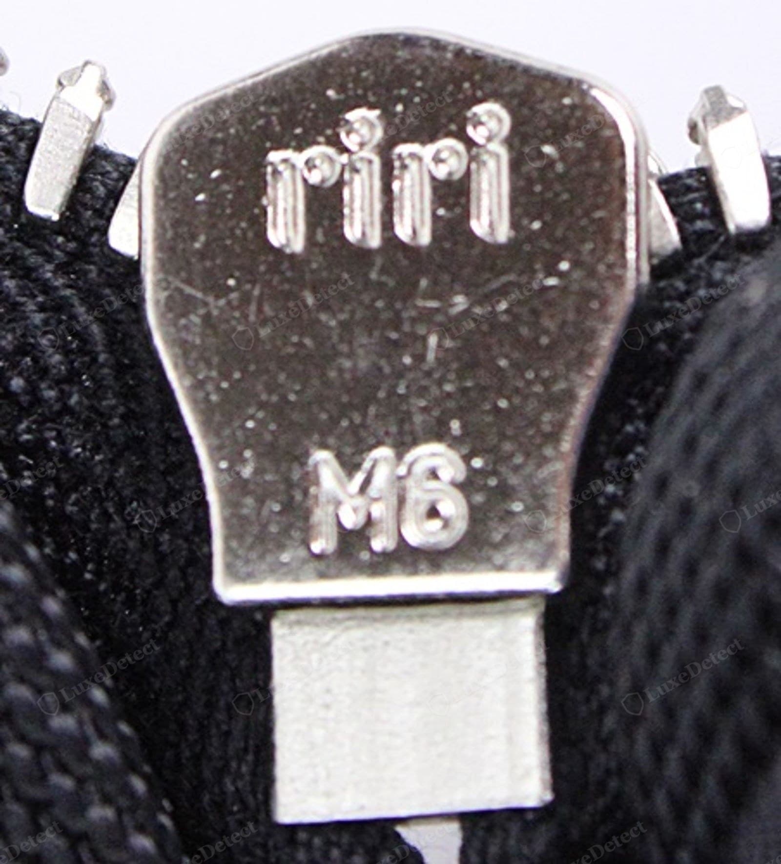Genuine Prada Re-Edition zipper — the slider underside carrying a clean maker's mark, teeth even, tape matched to the nylon