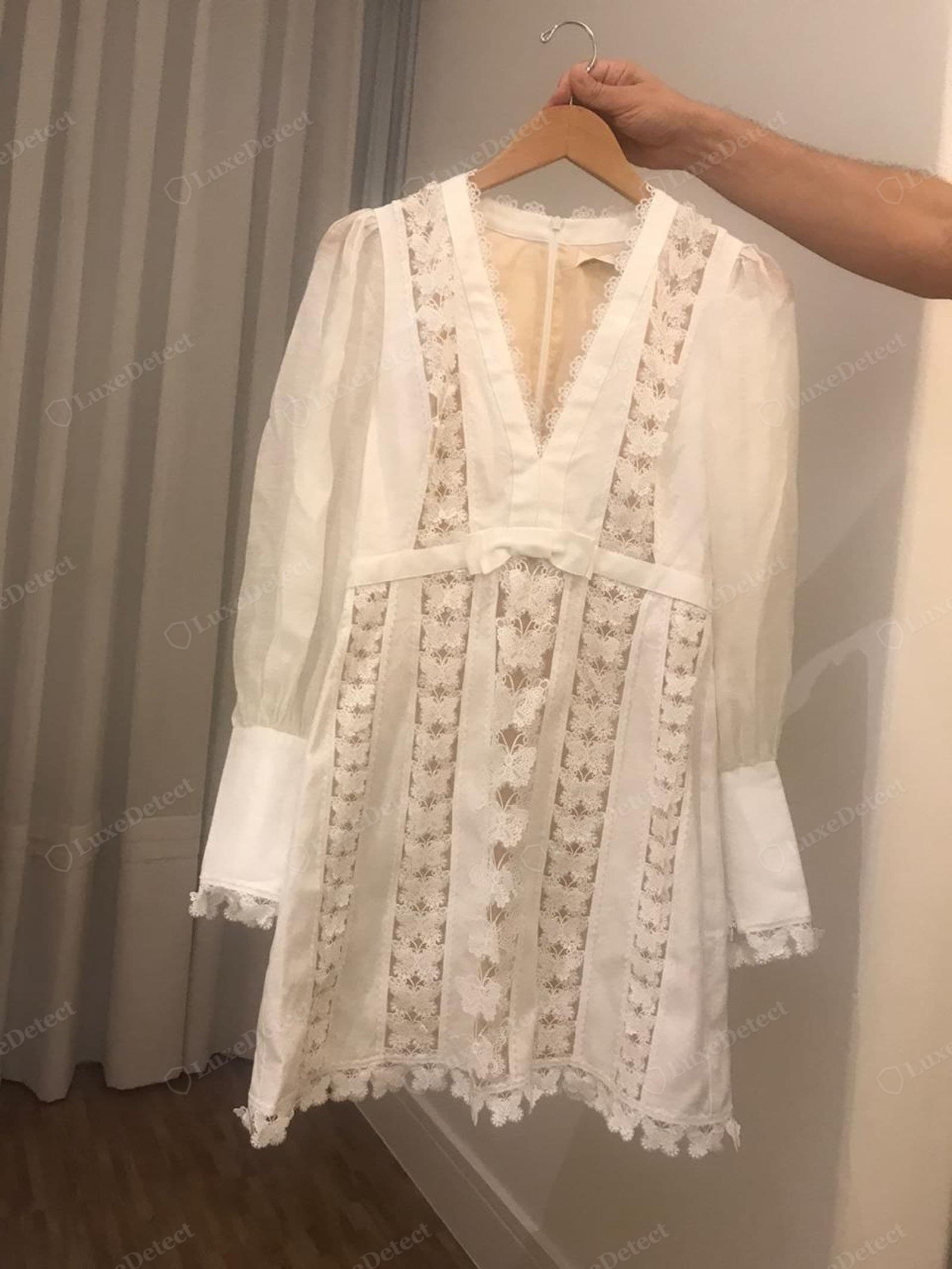 Genuine Zimmermann trim work — a white broderie dress with engineered lace panels running vertically, aligned to the seams, applied flat, finished with an even scalloped hem
