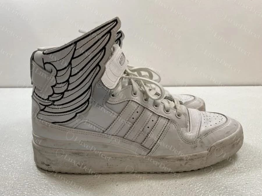 Genuine adidas Jeremy Scott Wings 4.0 white Forum Hi sneaker, with a black-outlined drawn wing on the ankle strap and white three-stripe side panels, worn with creasing and sole dirt