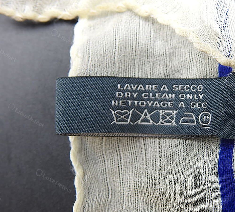 Authentic McQueen skull scarf hem — a rolled silk cord edge with the "100% SETA - SILK - SOIE, MADE IN ITALY" content tag, confirming the silk-blend construction