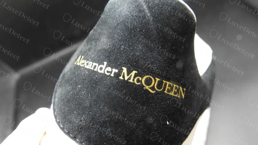 Counterfeit heel tab in black suede with the gold Alexander McQueen logo, well formed and evenly pressed