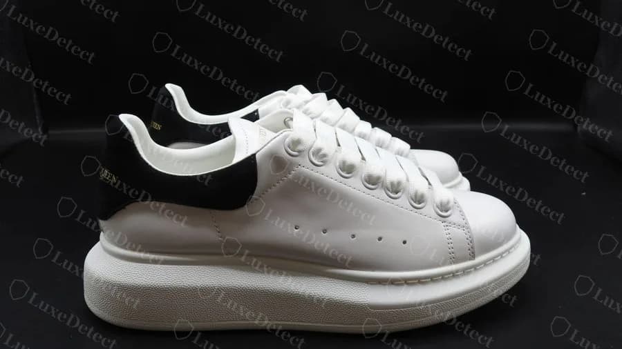 Counterfeit McQueen Oversized pair from the side: white leather, black suede heel tab, thick rounded midsole and gold heel logo, all convincingly copied