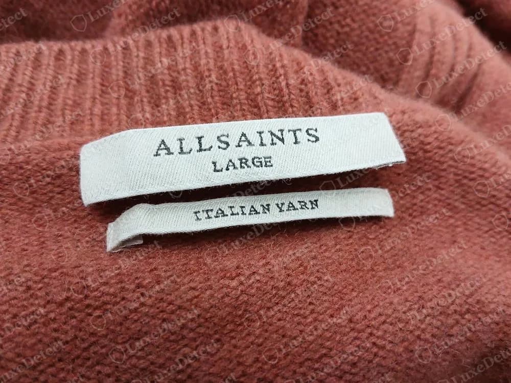 Genuine AllSaints woven neck label reading ALLSAINTS LARGE above a second narrower woven label reading ITALIAN YARN, inside a rust-coloured knit