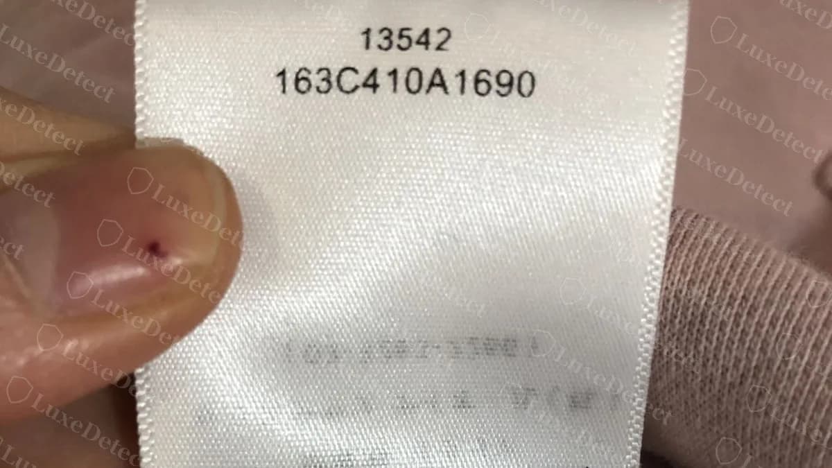 Pflegeetikett einer Balenciaga-Fälschung aus unserem Archiv: glänzendes weißes Satinband mit einem Style-Code, unscharfer verschmierter Druck in der Mitte und Made In ITALY TOP am unteren Rand