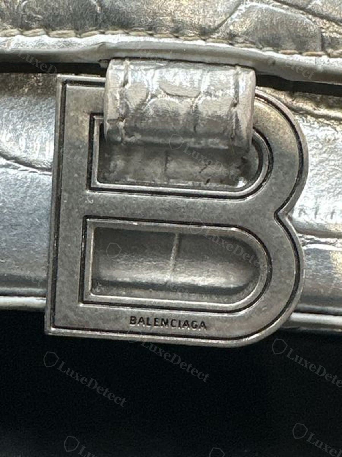 Counterfeit Hourglass B hardware on a croc-embossed bag: the plate reads close at a glance, but weight and engraving depth are where a fake gives itself away in hand, not in a photo