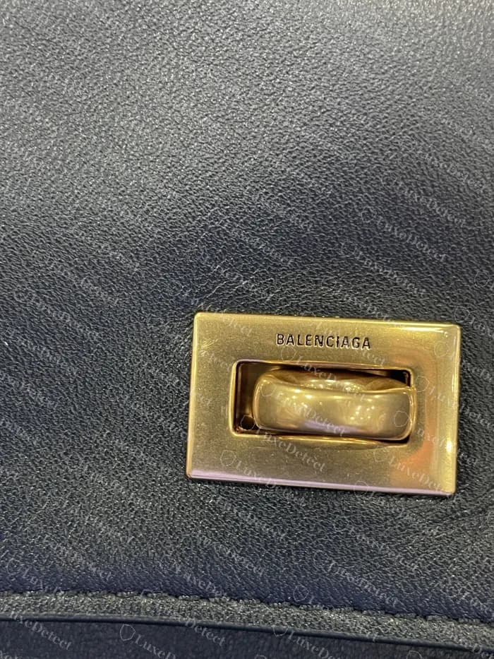 Placa do fecho giratório de uma Rodeo autenticada: “BALENCIAGA” gravado acima da barra giratória, acabamento fosco escovado em tom dourado, sem brilho de espelho