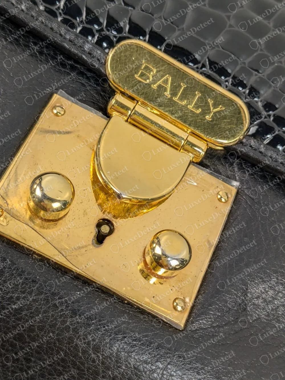 Genuine Bally gold-tone turn lock engraved BALLY on a black bag with a crocodile-embossed flap