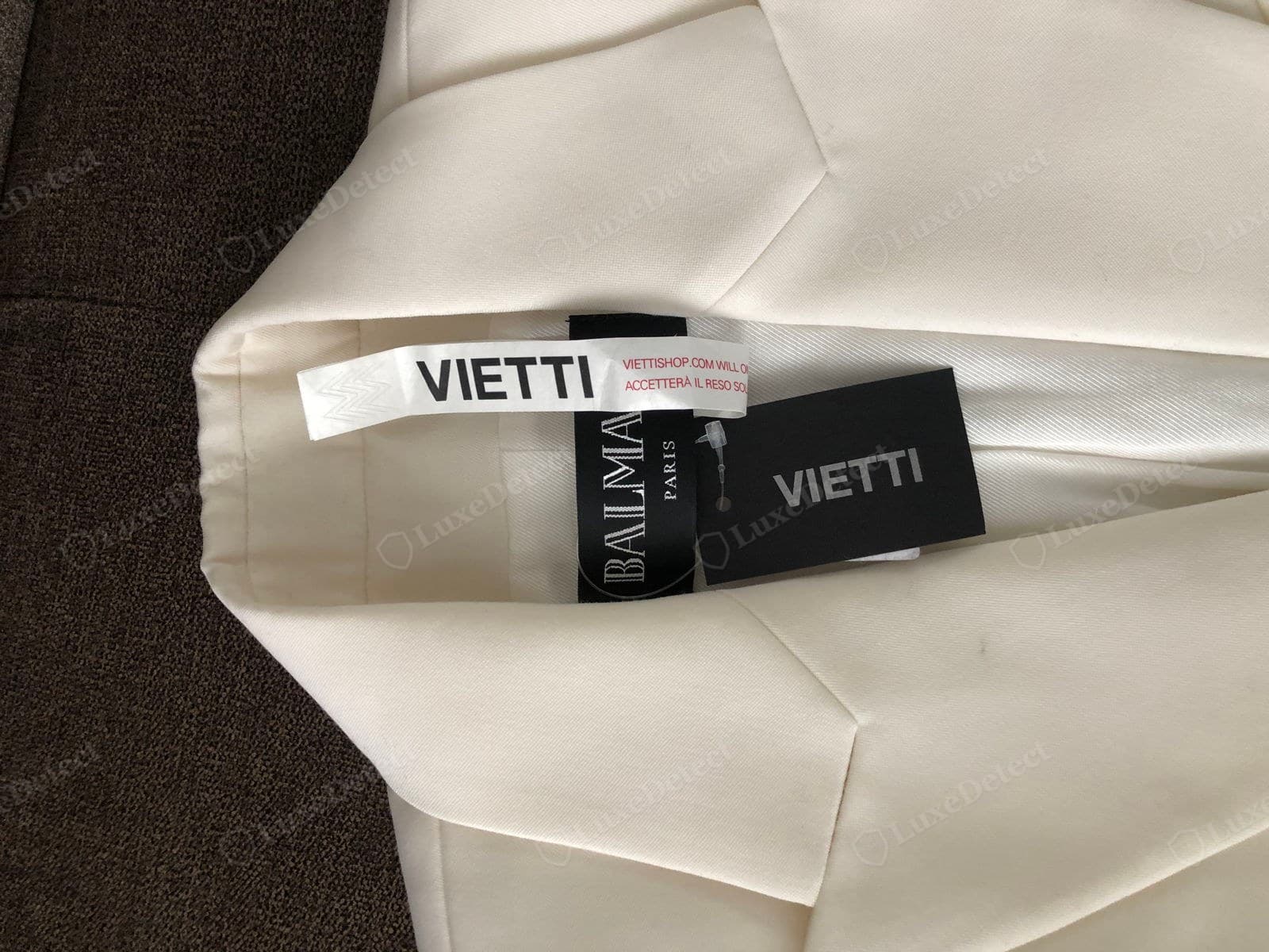 Genuine Balmain provenance — an ivory blazer with the black "BALMAIN PARIS" woven label plus a retailer's own hang tag and security tag still attached, the kind of documentation a legitimate stockist purchase carries