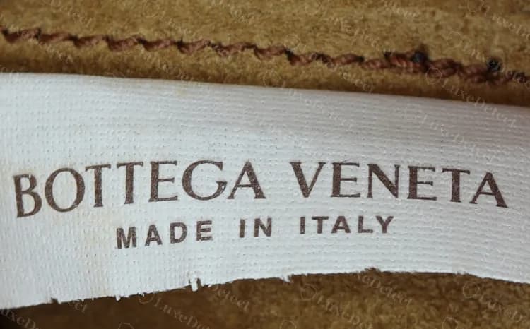 Genuine white woven label: BOTTEGA VENETA in brown serif capitals over MADE IN ITALY in smaller spaced capitals