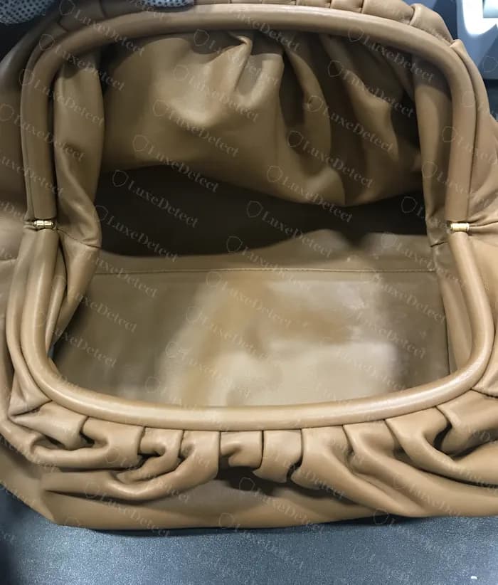 Pouch original aberta: o tubo da armação coberto de couro, franzidos macios ao longo do topo, pequenas dobradiças cilíndricas douradas em cada ponta e um forro de couro liso