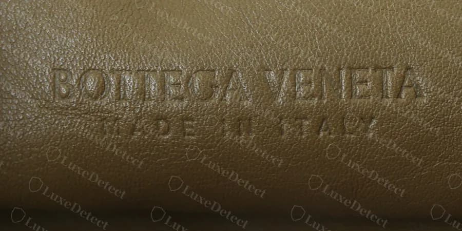 Sello en caliente de un Pouch genuino: "BOTTEGA VENETA" sobre un "MADE IN ITALY" muy espaciado, en bajorrelieve sin tinta sobre el cuero del forro