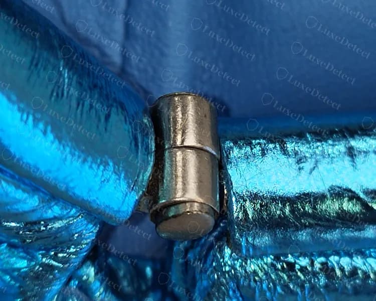 Dobradiça de uma Mini Pouch original em couro metalizado: um cilindro maciço de metal onde as duas metades da armação se encontram