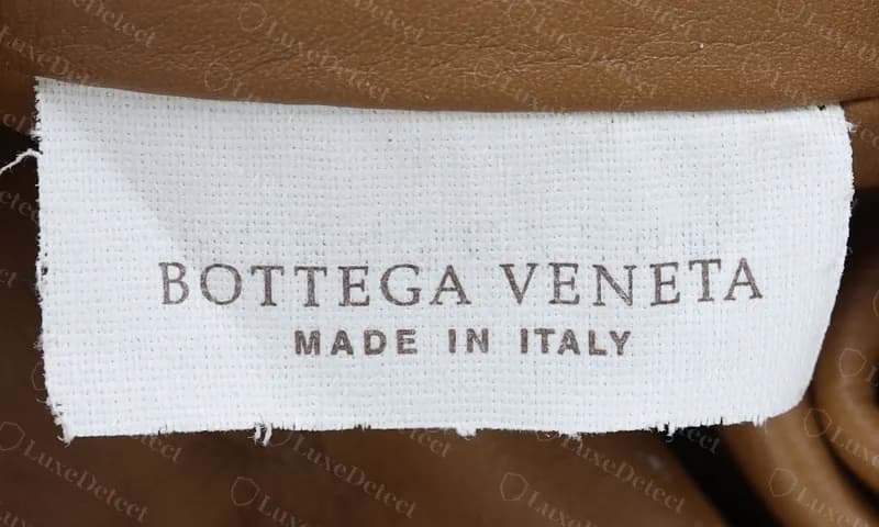 Genuine Pouch brand label: "BOTTEGA VENETA" in a light brown serif over a bolder, letter-spaced "MADE IN ITALY"