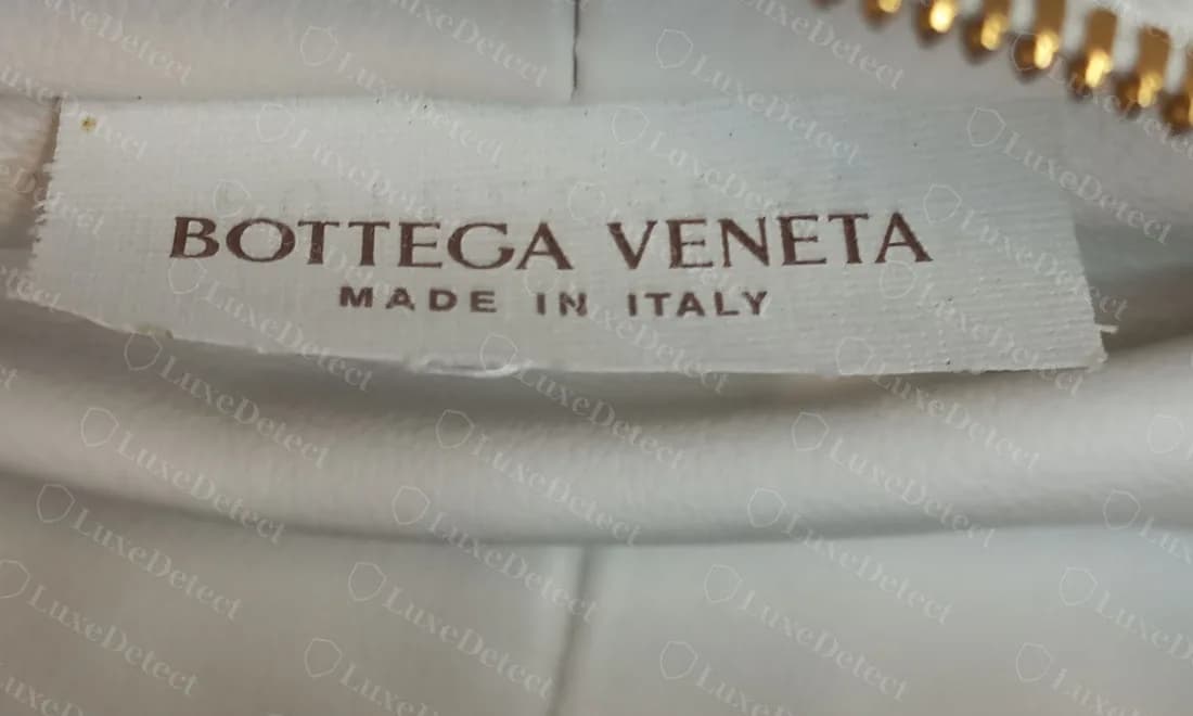 Genuine white woven brand label reading BOTTEGA VENETA over MADE IN ITALY, sewn into the lining