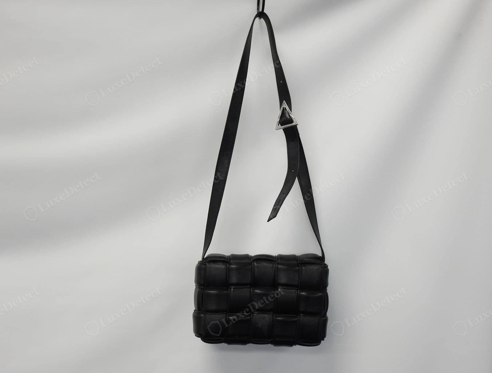 Counterfeit Padded Cassette: the weave has too many squares and they are individually too small, the cushions are under-stuffed and flat, the strap is thin, and the buckle is a shiny open silver triangle instead of an engraved matte plate