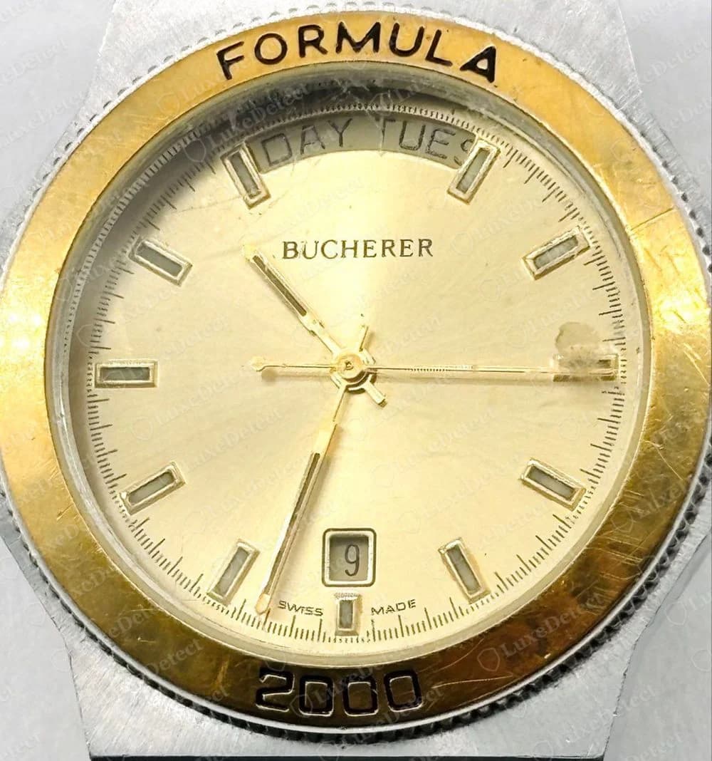 Genuine Bucherer Formula 2000 quartz dial: champagne dial with BUCHERER in small capitals, a day window reading DAY TUES, a date window and SWISS MADE near the bottom, inside a gold-tone bezel engraved FORMULA and 2000