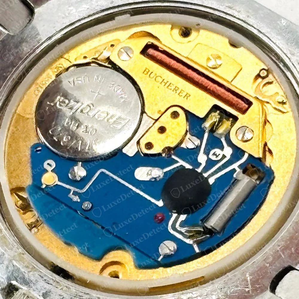 Genuine Bucherer Formula 2000 quartz movement seen with the case back off: a gold-coloured plate printed BUCHERER, a copper coil, a blue circuit board and a battery