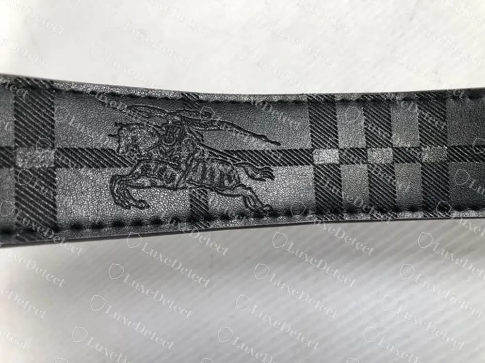 Reverso de un cinturón dictaminado como falso en piel negra, con un caballero grande en relieve sobre unos cuadros, algo que no tenían los reversos originales que comparamos