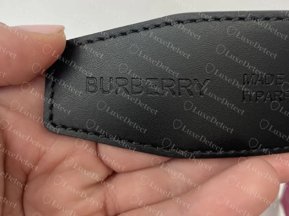 Reverso original de un cinturón reversible con BURBERRY y Made in Italy presionados en piel negra