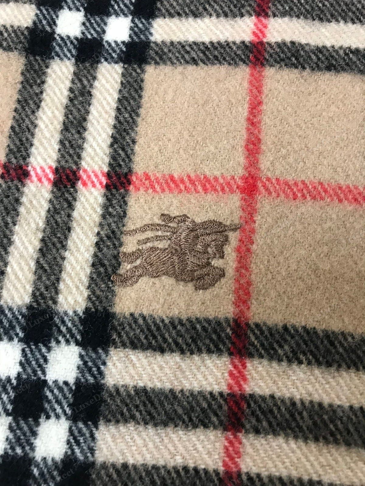 Logo de una bufanda Burberry falsa: un "BURBERRY" borroso, mal proporcionado o estampado, o con la tipografía incorrecta