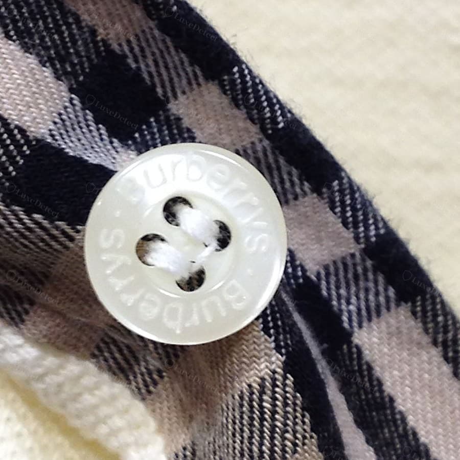Botón Burberry falso: un anillo con el nombre "Burberrys" dos veces sobre una resina turbia y vidriosa, el grabado superficial y blando, el hilo del ojal deshilachado