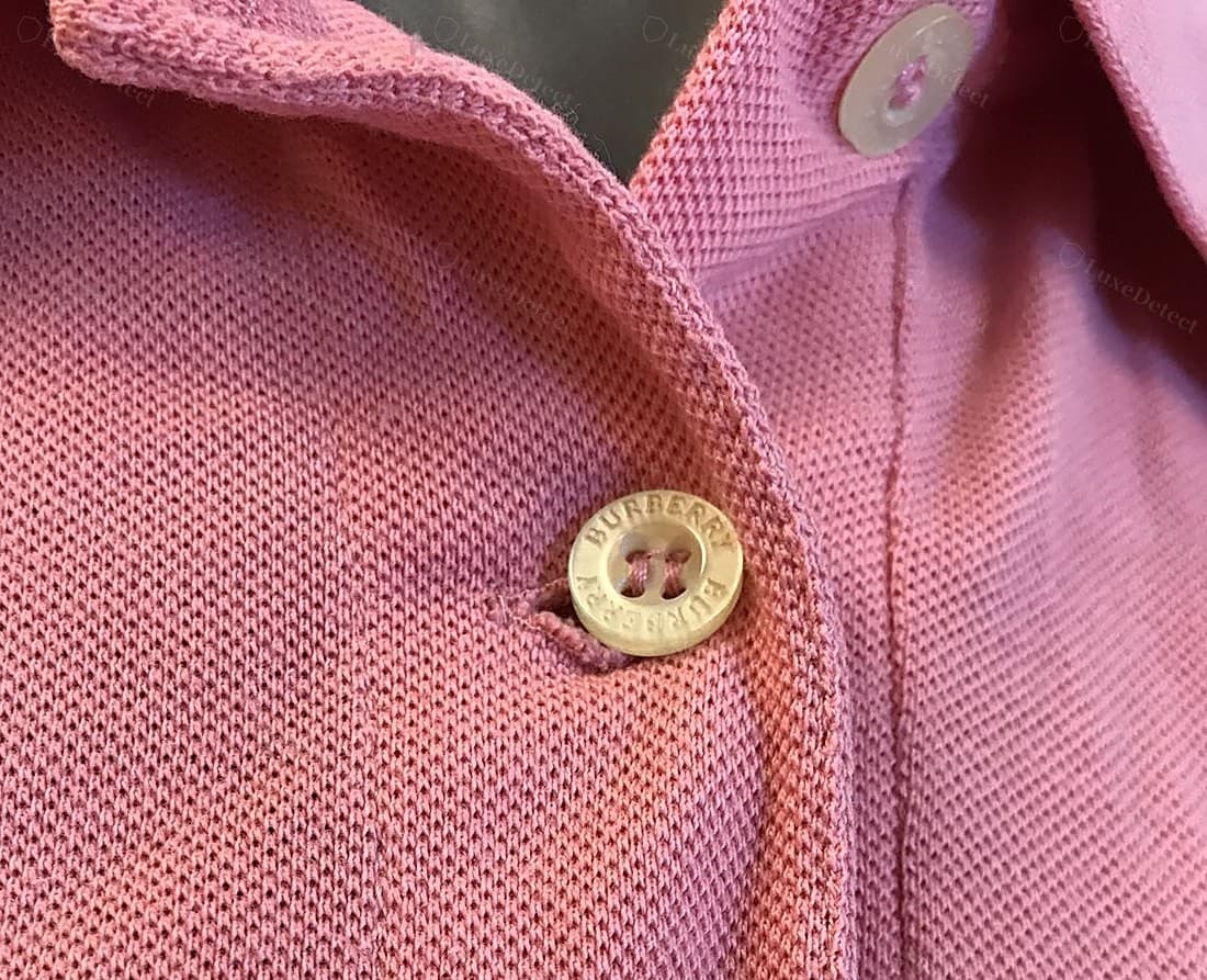Patte de polo Burberry authentique : le revers à carreaux monté avec une surpiqûre soignée, une boutonnière coupée net et densément piquée, le col qui roule doucement sans pli dur