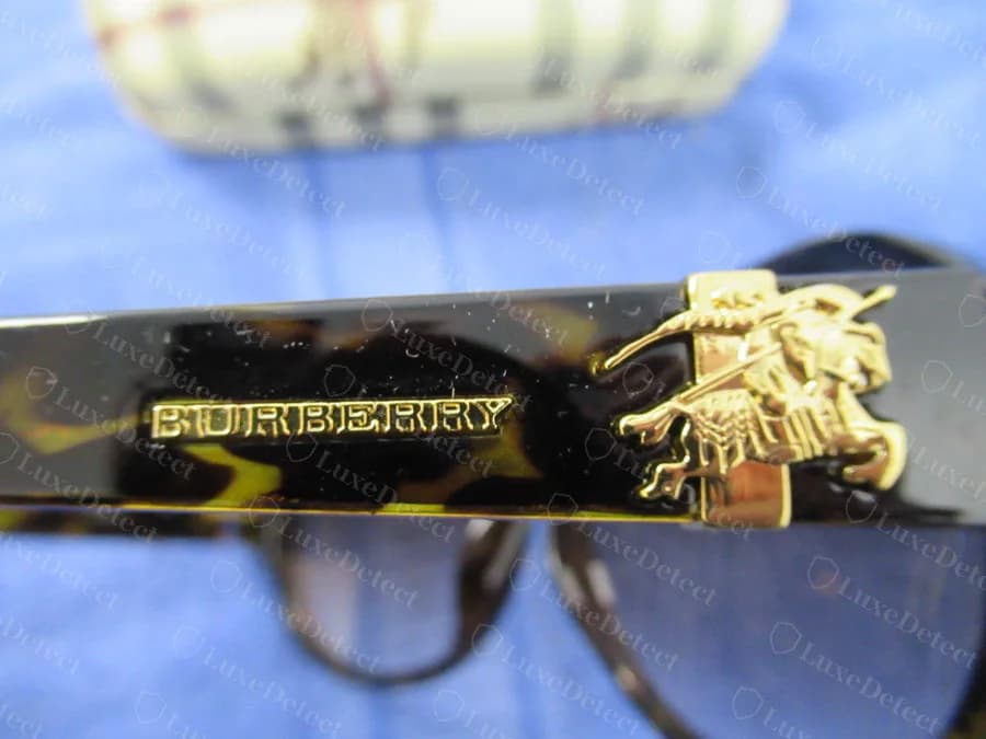 Equestrian knight logo on a counterfeit's gold hinge tab; compare only against authentic examples from the same mounting location.