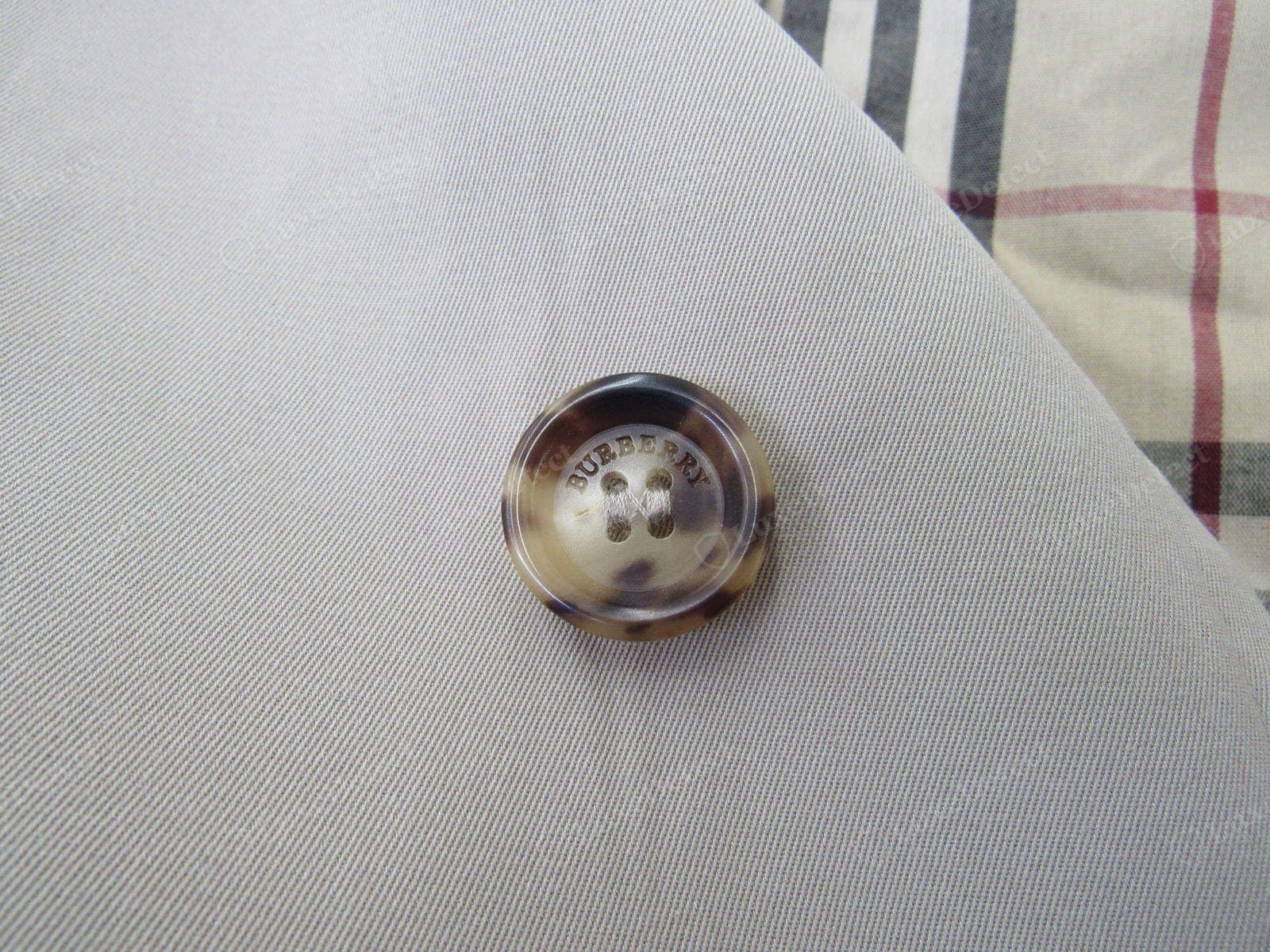 Bouton de trench Burberry authentique : résine bombée façon corne, gravure BURBERRY LONDON nette, cousu serré sur un pied