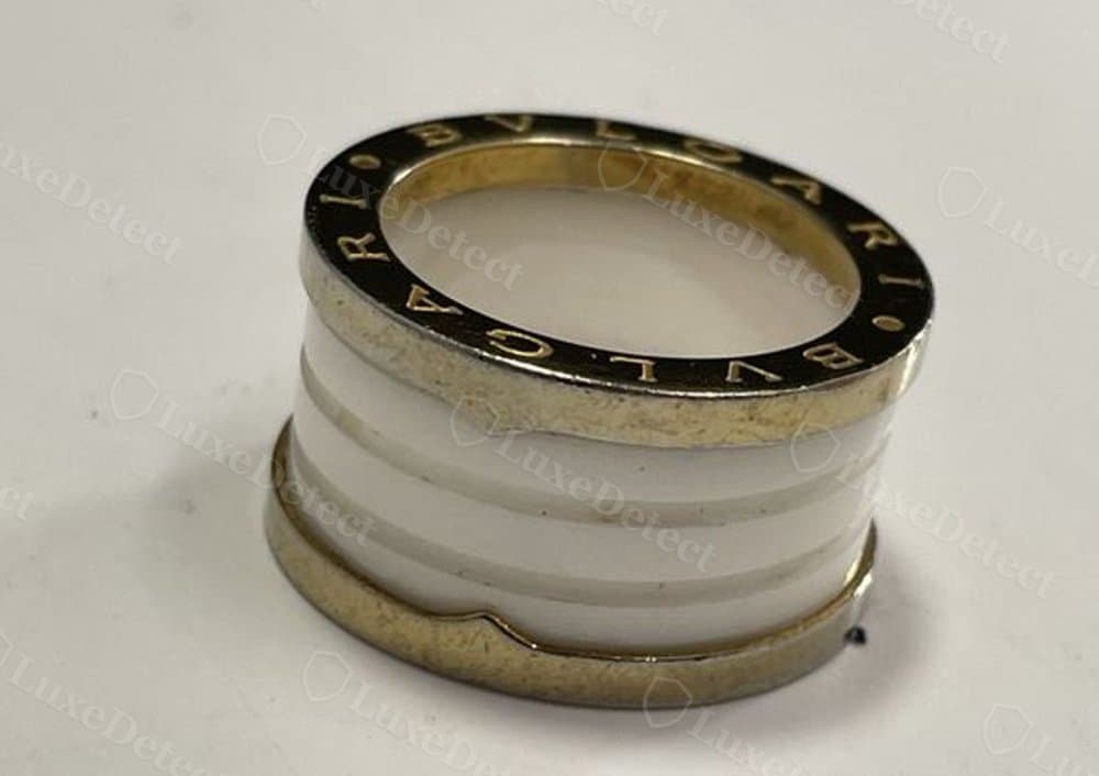 Counterfeit engraving on a gold-tone ring: rougher plating texture and less even letter spacing than the genuine band above.
