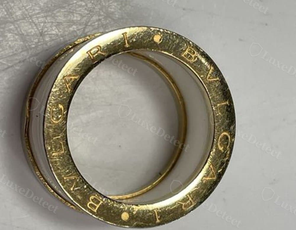 A counterfeit ring's engraving: rougher plating texture and uneven letter spacing.